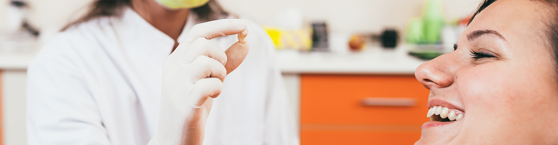 dentist holding extracted tooh in front of smiling woman